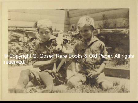 Anonymous Photographer. Untitled. Two Boys in Scouts’ Uniforms Wearing Party Hats, Posing with Their Jack Russell Terrier Wearing a Paper Cup as a Hat.